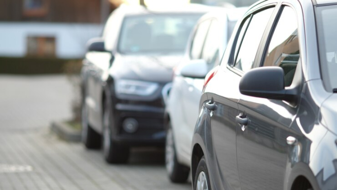 Stāvošasa automašīnas tumšā tonī no sāna