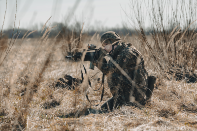 Persona militārā formas tērpā lauka vidū