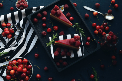 Sarkanas kūciņas uz melna šķīvja, viss izdekorēts ar sarkanām ķiršogām