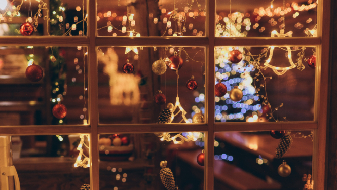 Skaisti izrotāts logs Ziemassvētku noskaņās. Ar lampiņām, sarakanām bumbiņām un egles atspulgu.