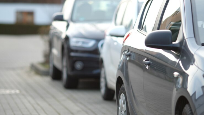 Stāvošasa automašīnas tumšā tonī no sāna