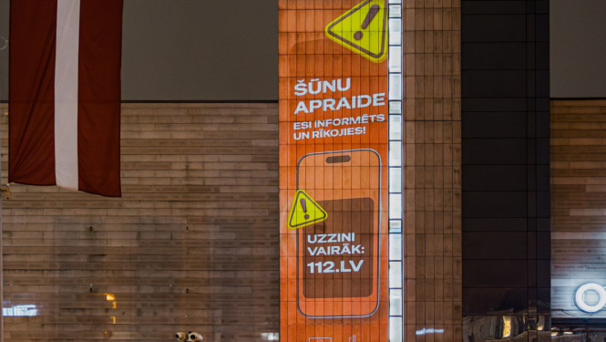 Brīdinājuma paziņojums orandžā krāsā uz pilsētvides ekrāna