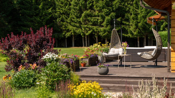 Terase ar diviem krēsliem un apkārt košas, krāsainas vasaras puķes