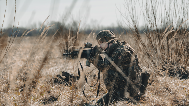 Persona militārā formas tērpā lauka vidū