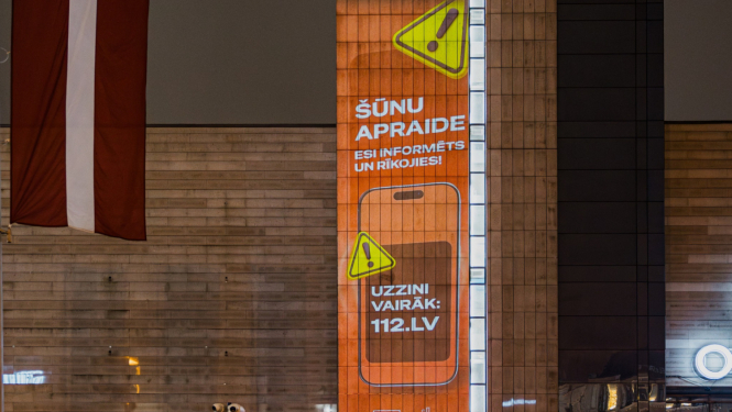 Brīdinājuma paziņojums orandžā krāsā uz pilsētvides ekrāna